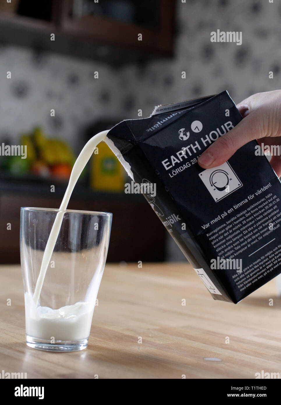 Milk in a glass. Information on a milk package about Earth hour Stock Photo  - Alamy