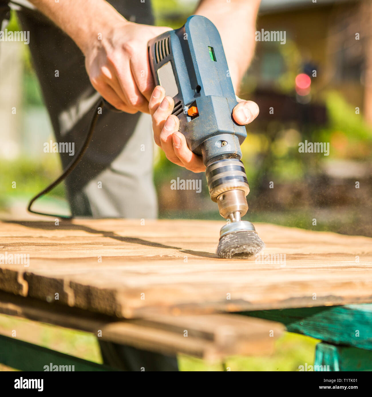 Hands man with electrical rotating brush metal disk sanding a piece of ...