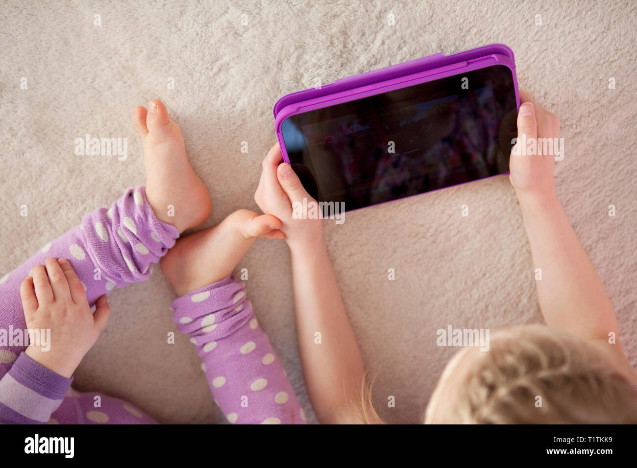 Overhead view of a child and toddler using a tablet device in a home environment Stock Photo