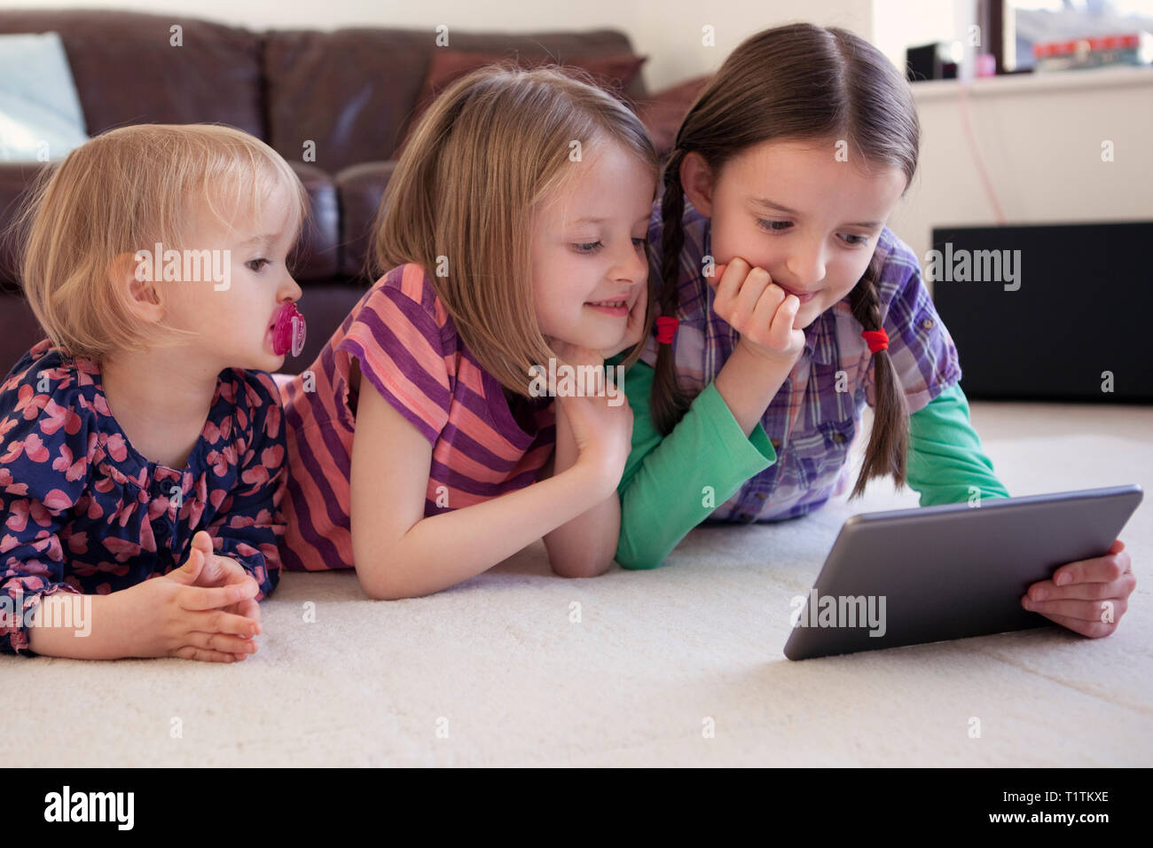 Three children using a tablet device together Stock Photo