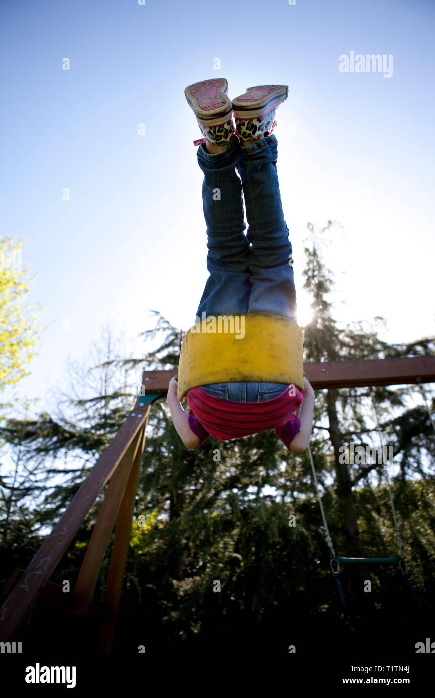 Child swinging on a garden swing on a sunny day with clear blue sky Stock Photo
