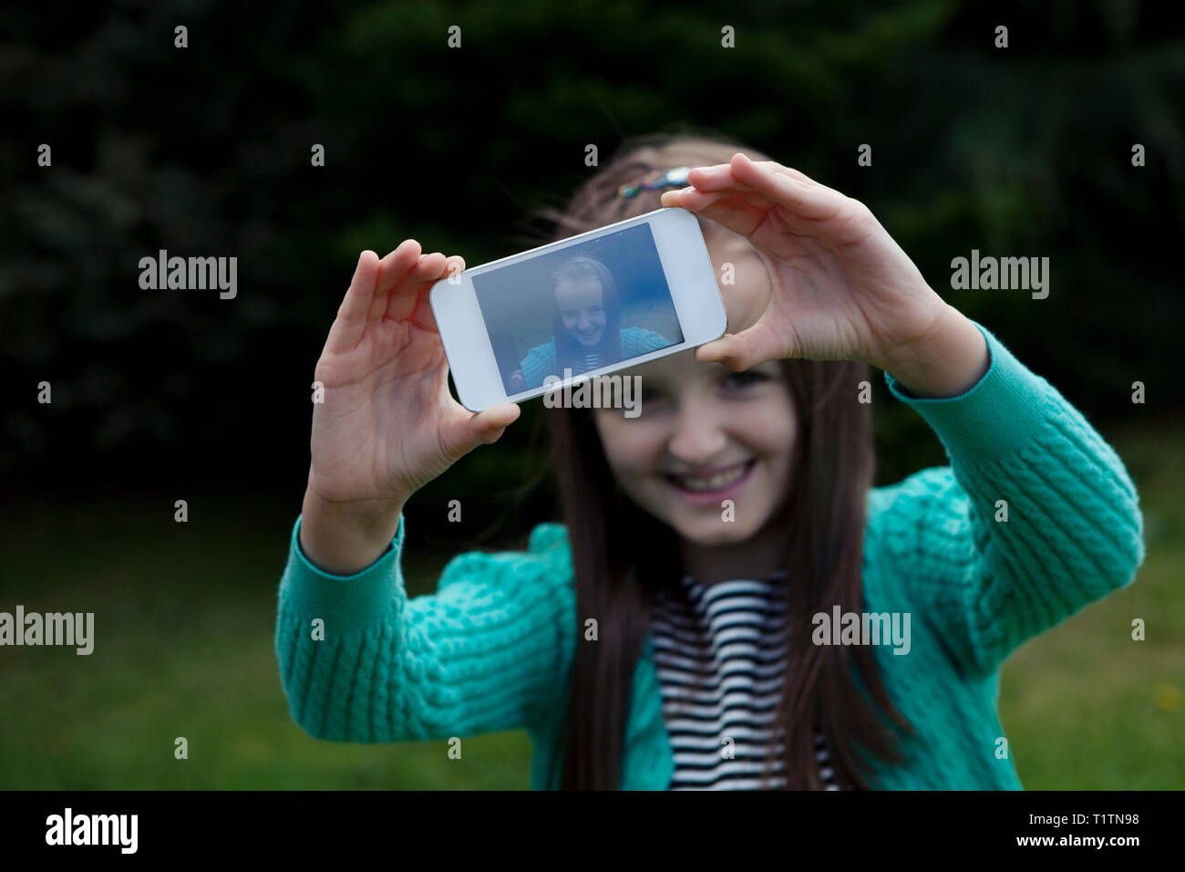 Smiling child using smartphone to take a selfie Stock Photo