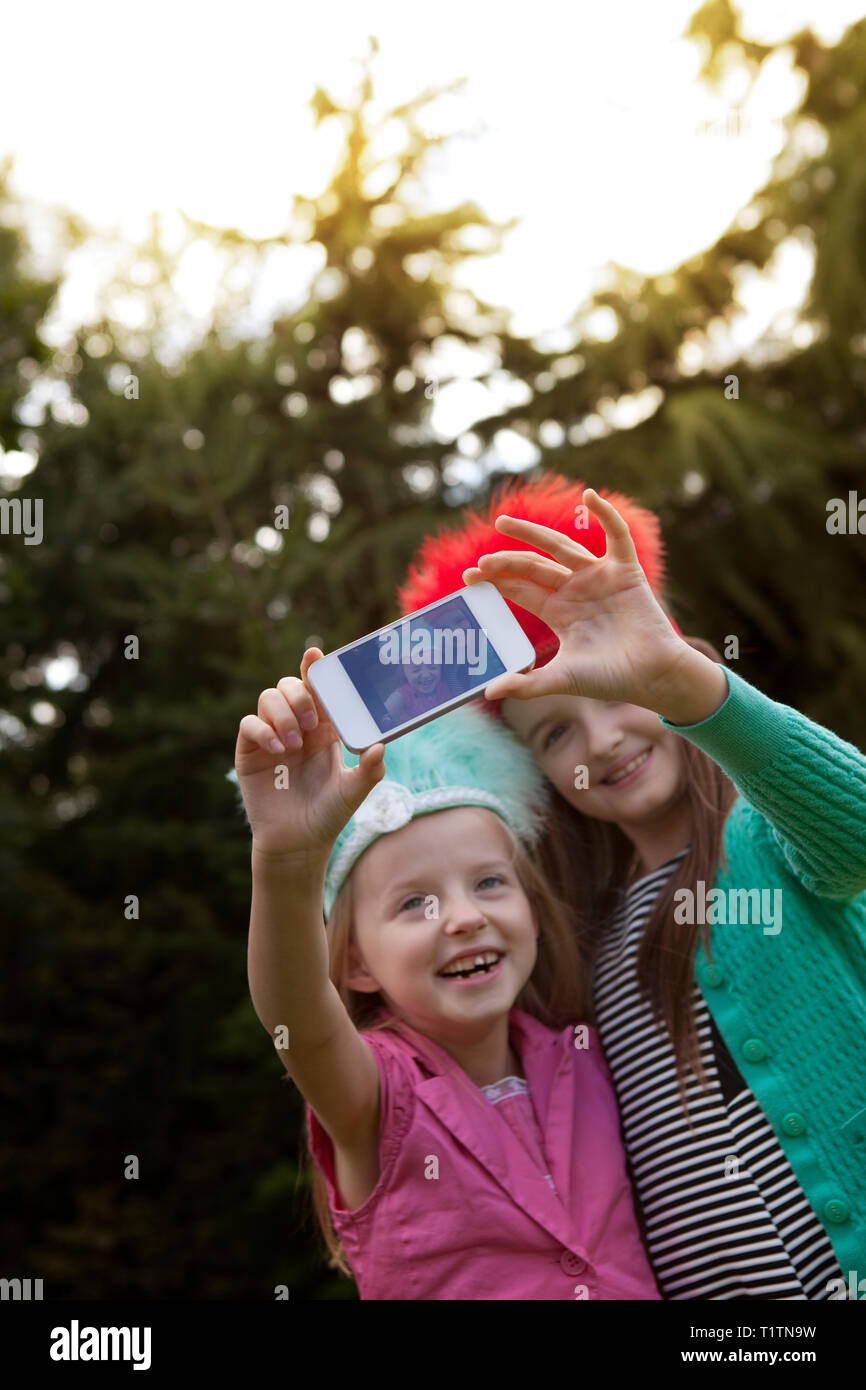 Two smiling children using a smartphone to take a selfie Stock Photo