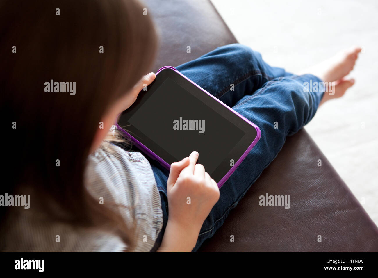 Over the shoulder view of girl using tablet device Stock Photo
