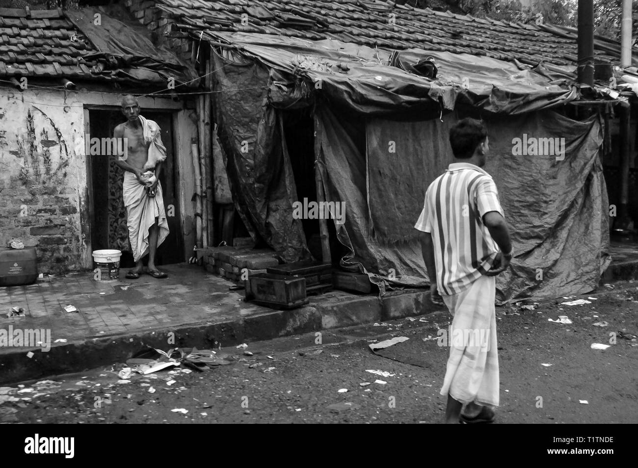 Man living in sidewalk slum bathing from a bucket on the sidewalk in Calcutta, India Stock Photo