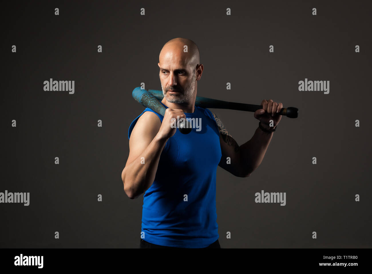 Handsome middle aged athlete doing muscle training with clubbels, studio background Stock Photo