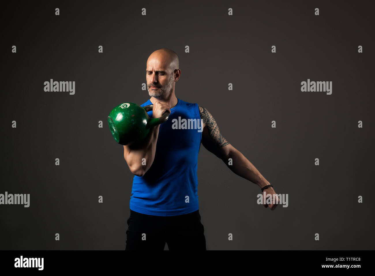 Studio portrait of middle aged athletic man in blue tank top with kettlebell Stock Photo