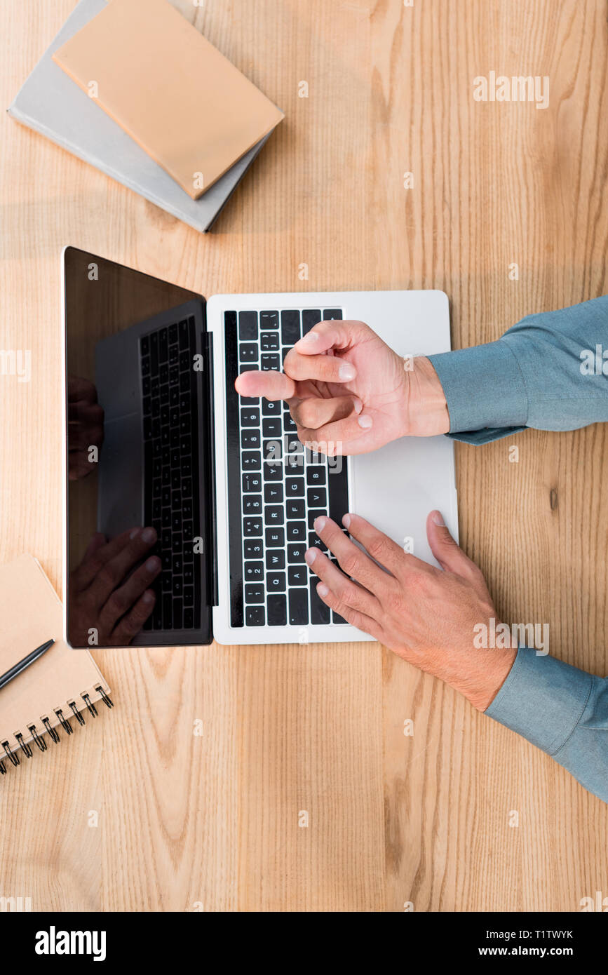 top view of man showing middle finger while using laptop with blank ...
