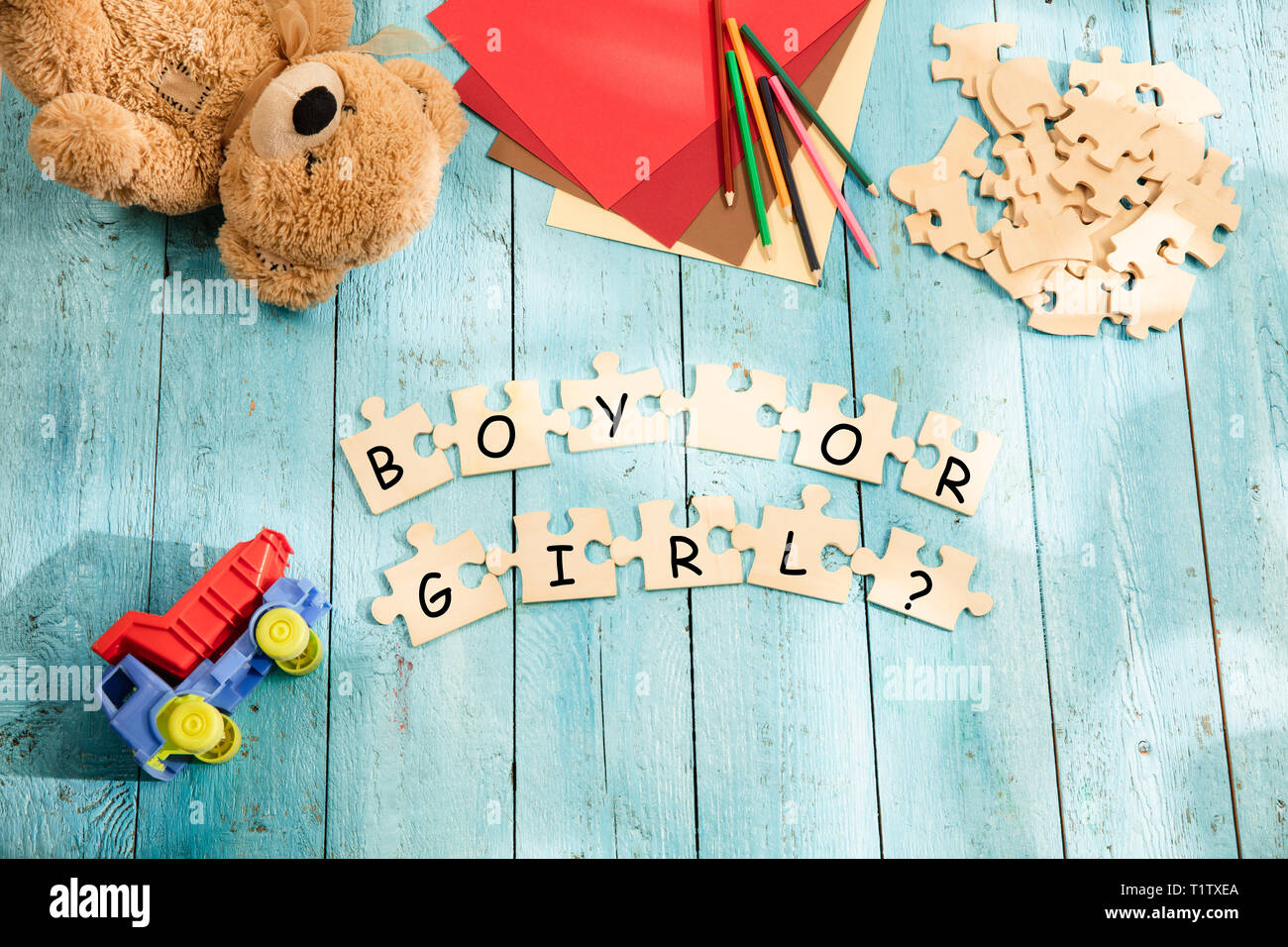 Stationery and words BOY OR GIRL made of letters, mock up and pieces of puzzles on wooden background. Concept of choosing baby name, parenthood and pregnancy. Stock Photo