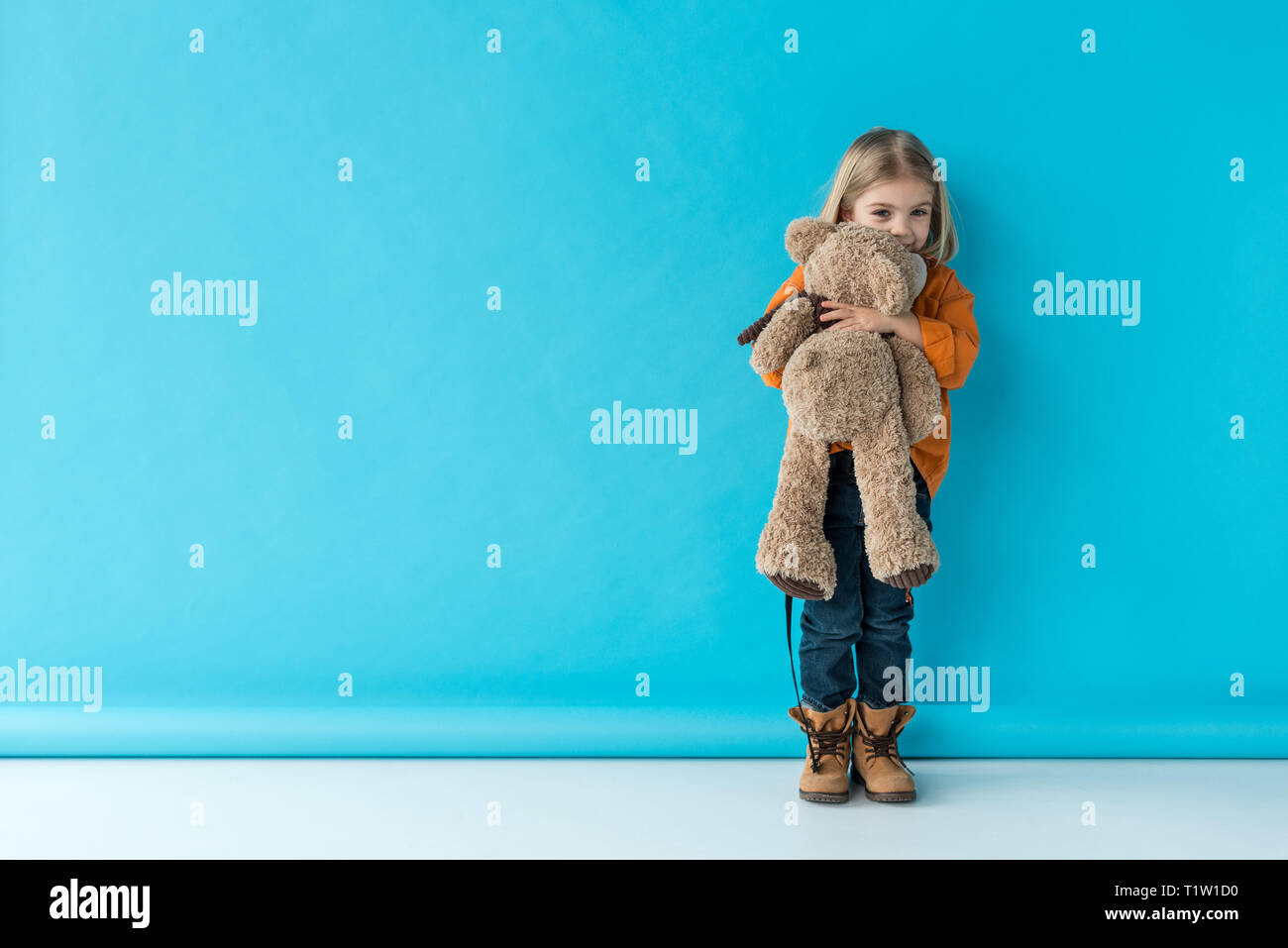 cute and adorable kid holding teddy bear on blue background Stock Photo ...