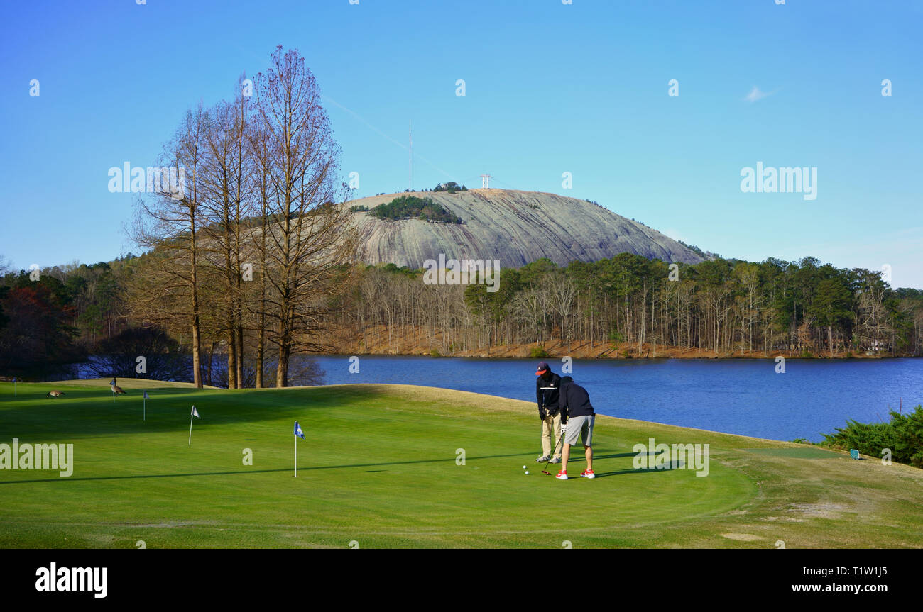 STONE MOUNTAIN, GEORGIA, USA - MARCH 19, 2019: Lakeside golf. Golf players at Stone Mountain Golf Club, in the background Stone Mountain Summit. Stock Photo