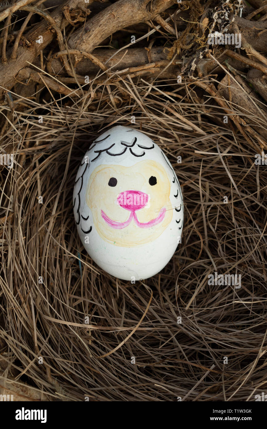 Detail of painted Easter egg with face of sheep in a birds nest Stock
