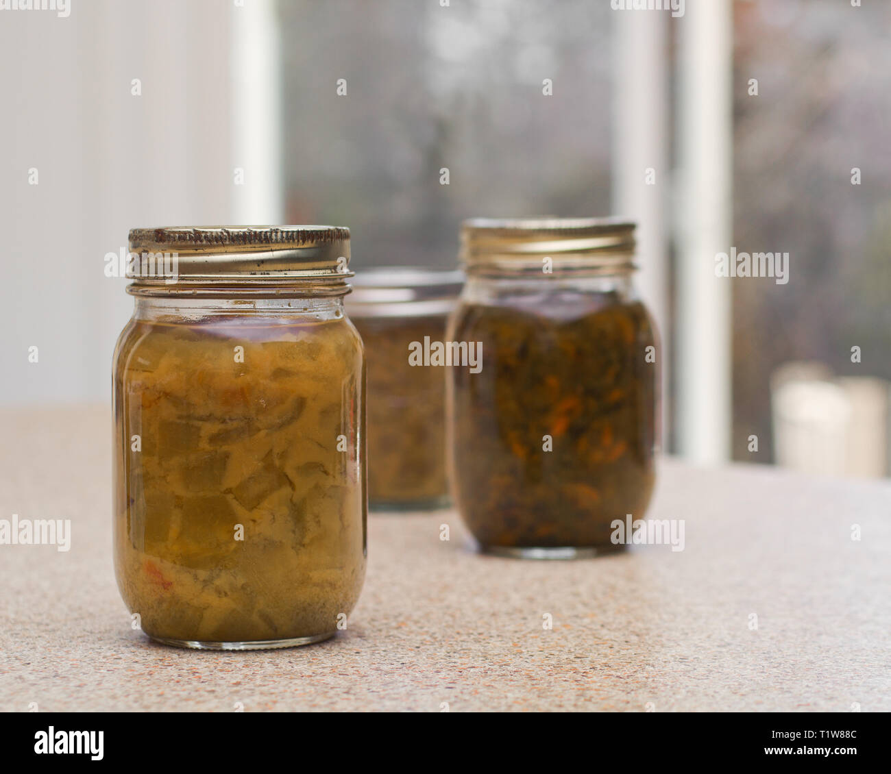 Homemade pickled relish bottles on kitchen counter top. Stock Photo