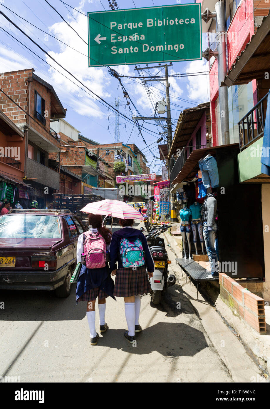 Colombia: Medellin. Two young girls in uniform, holding an umbrella to hide from sun, going to school Stock Photo