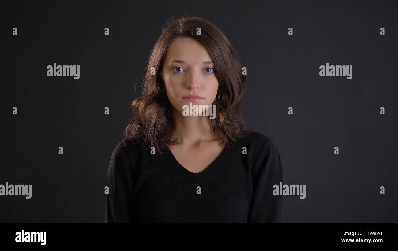 Portrait of fragile young brunette woman watching modestly and intently ...