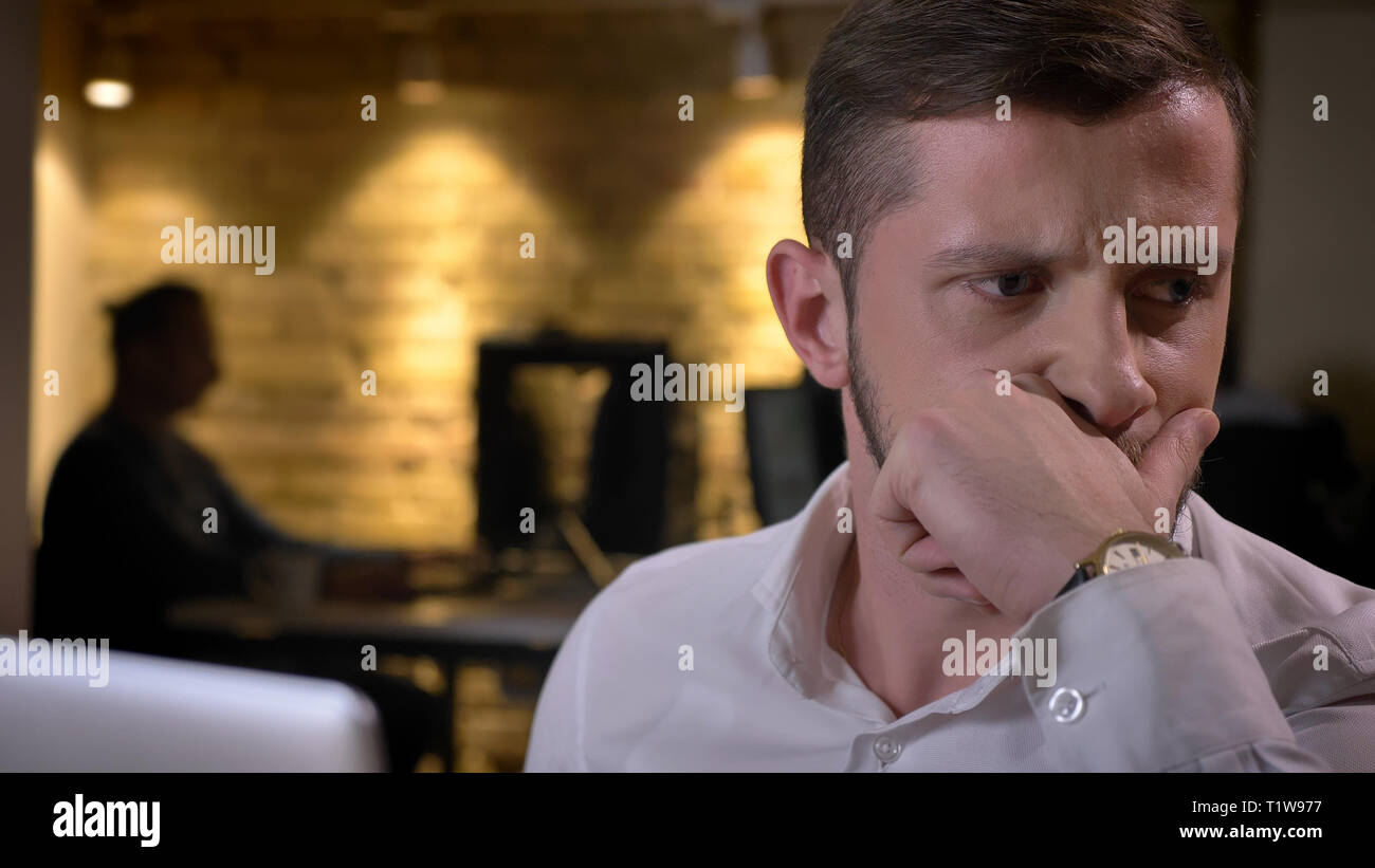 Closeup shoot of adult caucasian male employee being concerned and troubled indoors in the office Stock Photo