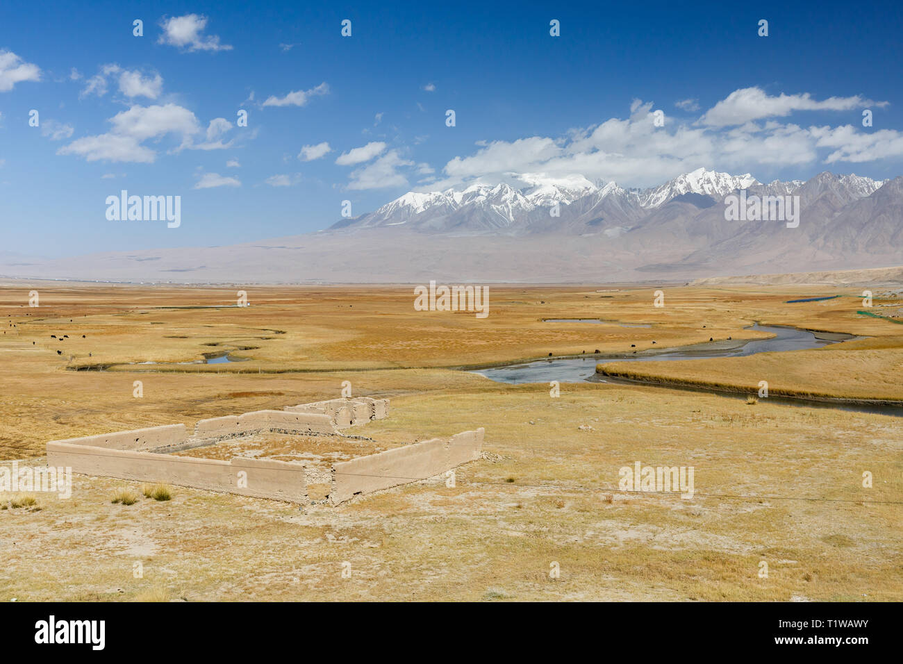 KARAKORUM HIGHWAY, XINJIANG / CHINA - October 3, 2017: View on Pamir Mountains - with a ruin, a river and yaks in the foreground (Karakorum Highway). Stock Photo