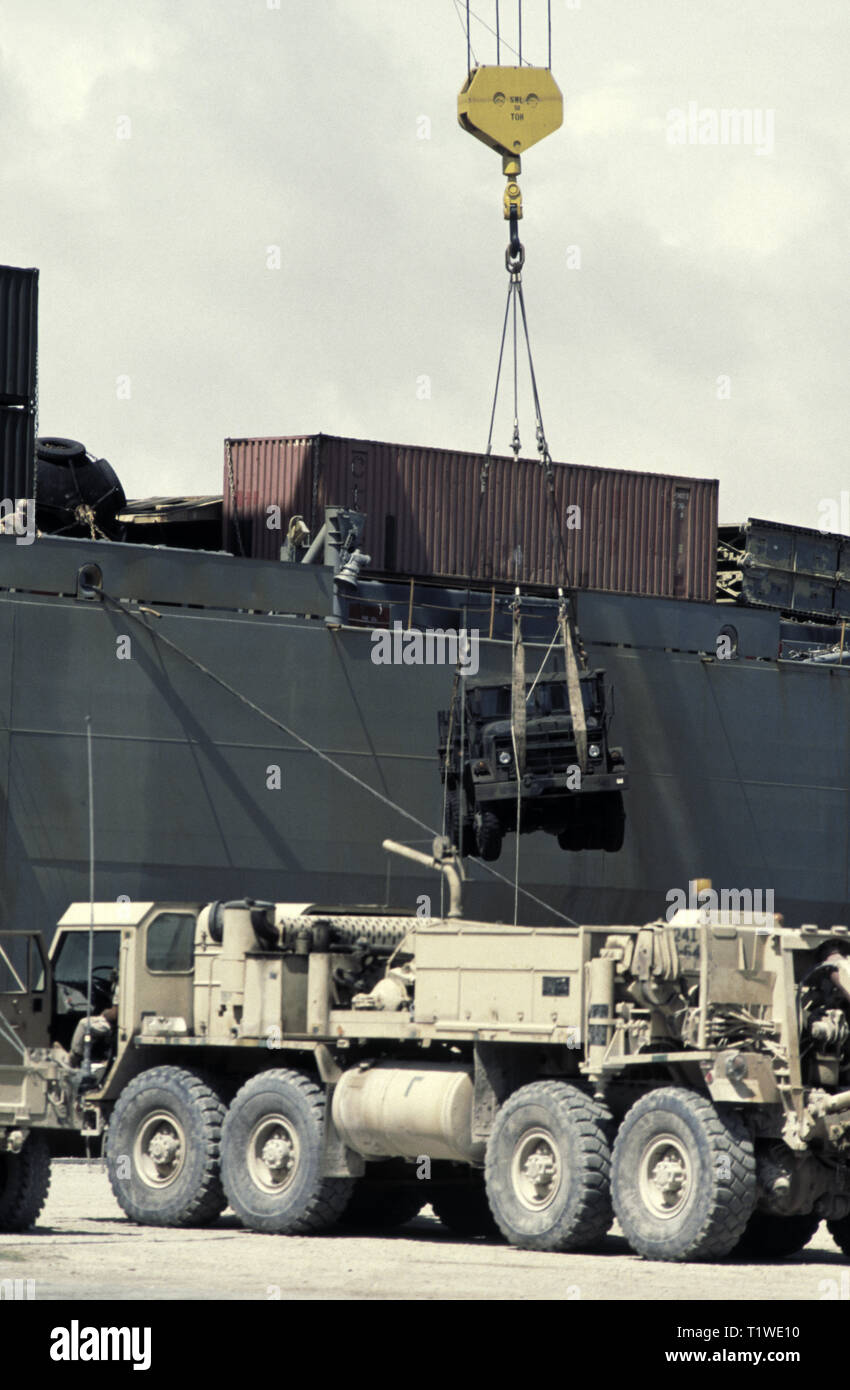 29th October 1993 An M939 5-ton truck being unloaded by a 50 ton crane from the United States Marine Administration vehicle cargo ship, USNS Denebola, in the new port in Mogadishu, Somalia. In the foreground is an M984A2 'wrecker' HEMTT (Heavy Expanded Mobility Tactical Truck) that was recently unloaded. Stock Photo
