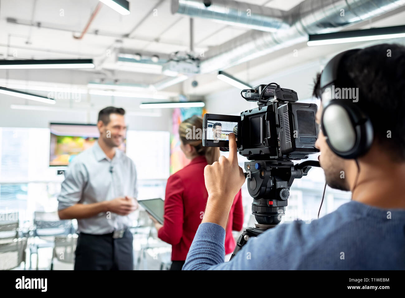 Happy businessman during corporate interview with female journalist. Manager answering question in office. Young woman at work as reporter with busine Stock Photo