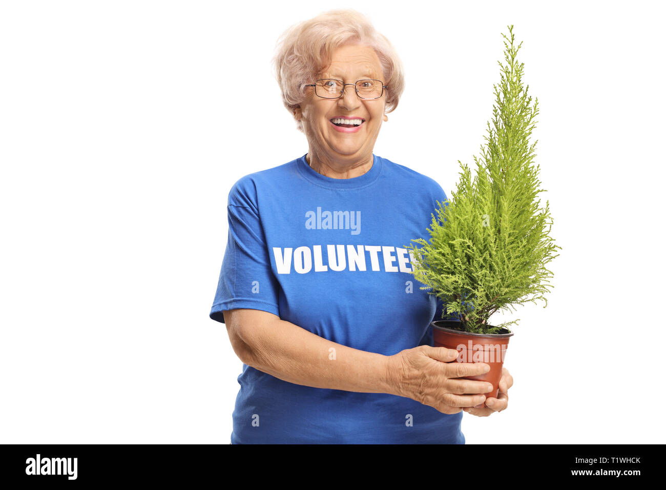 Elderly lady volunteer holding a plant and smiling at the camera isolated on white background Stock Photo