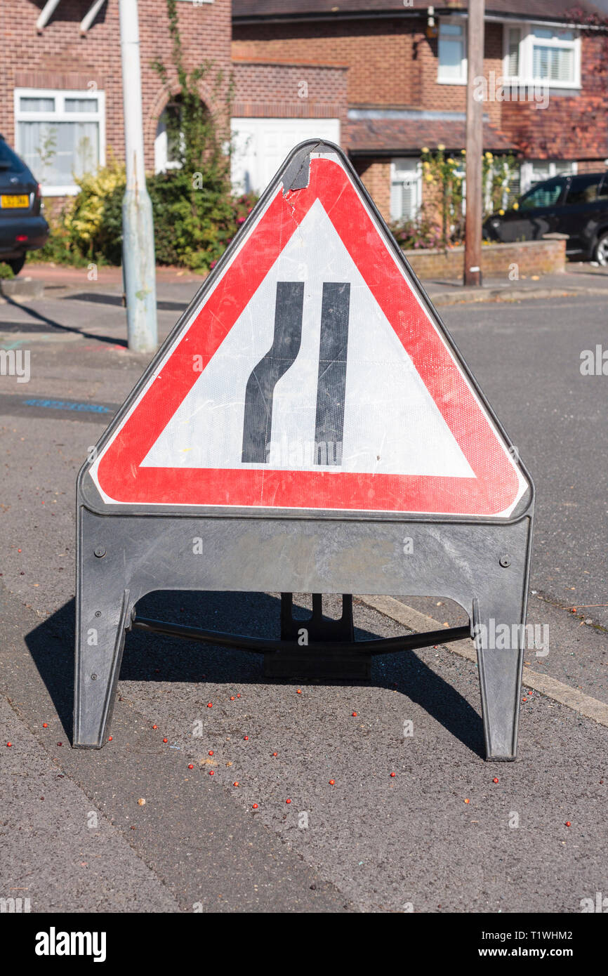 A temporary road sign (road narrows on the left) placed on the pavement Stock Photo