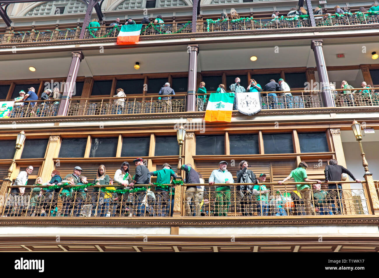 St. Patrick's Day celebrants enjoy the organic indoor 'street' party in the Arcade, a historic indoor mall with hotel in downtown Cleveland, Ohio, USA. Stock Photo