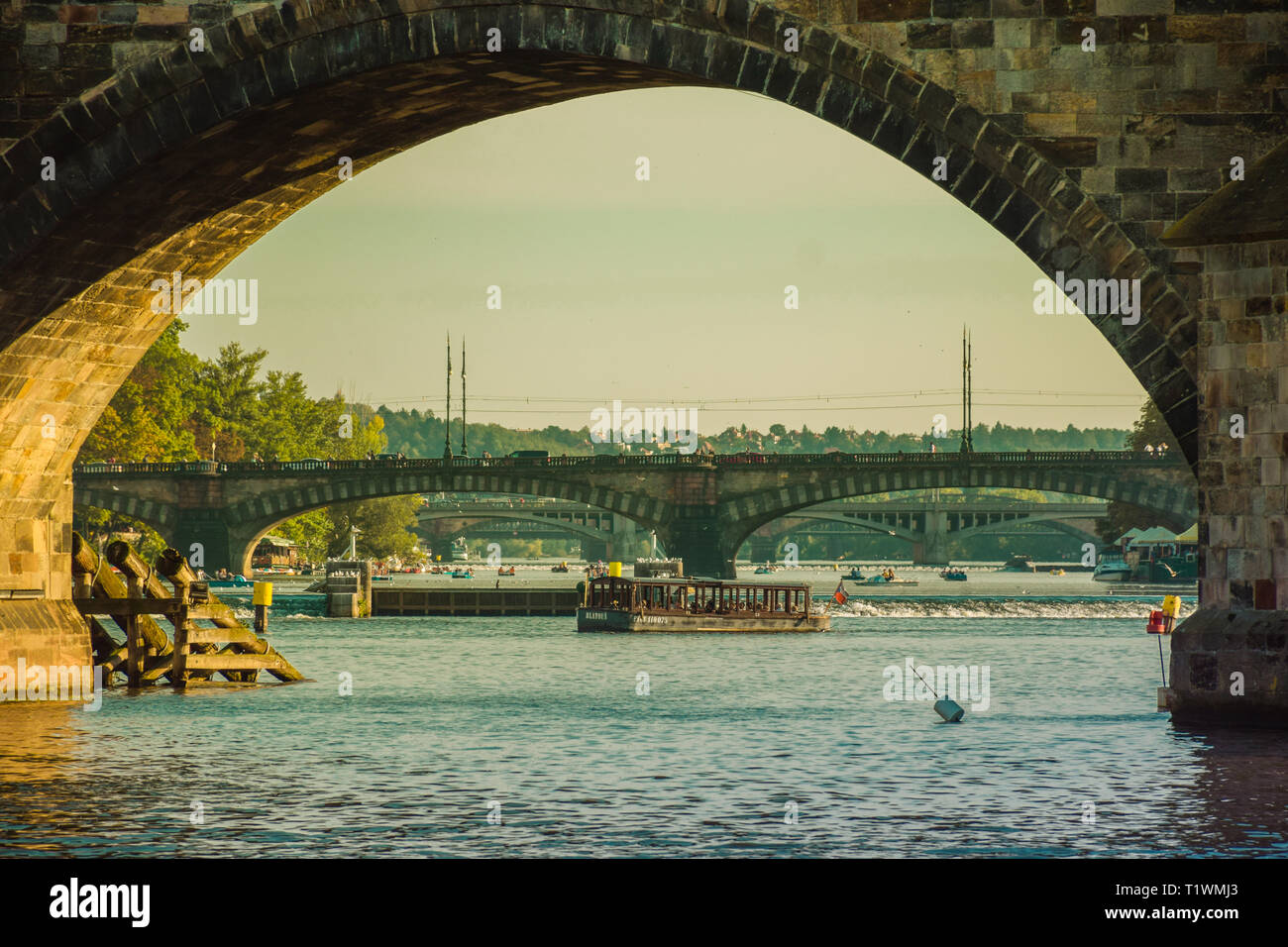 Prague, Czech Republic - September , 17, 2019: Tourists walking trought Charles Bridge, view from Vltava river level, showing the bridge spans, boats Stock Photo