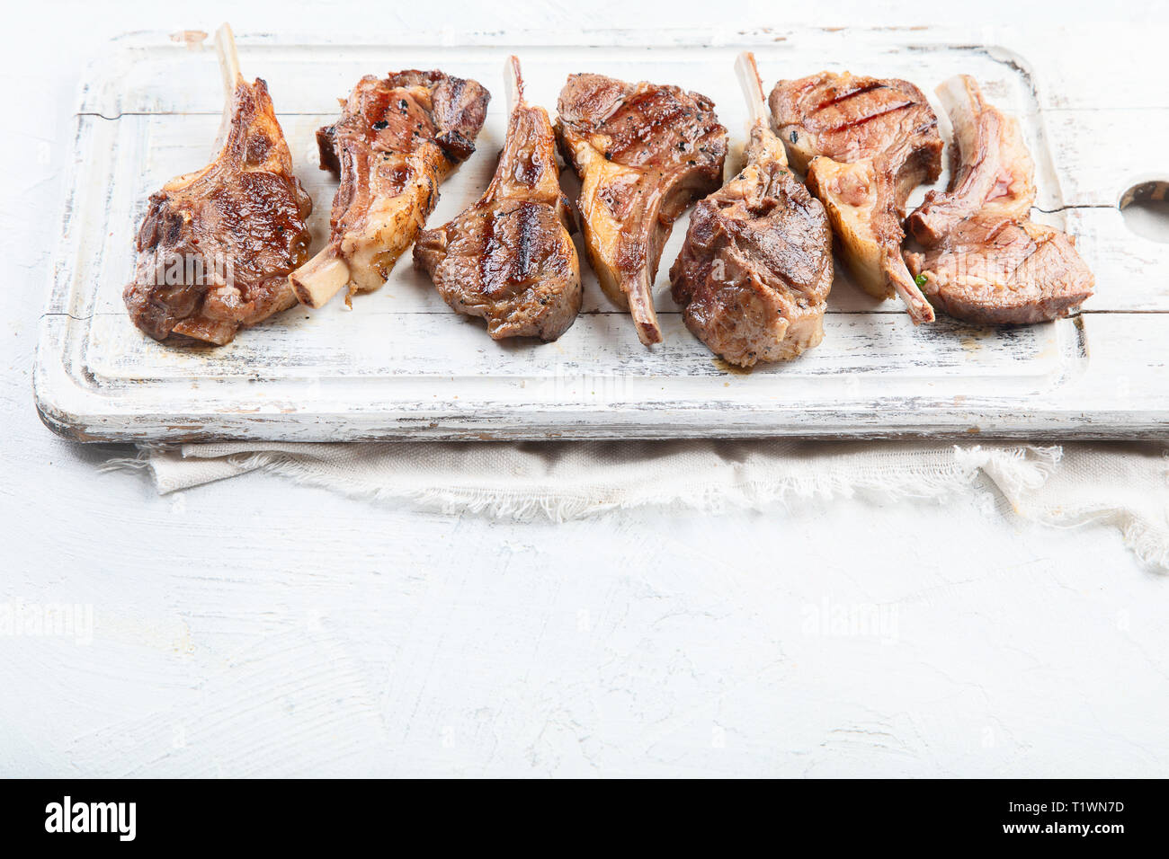 Grilled lamb ribs. Rack of lamb chop on white wooden board. Image with