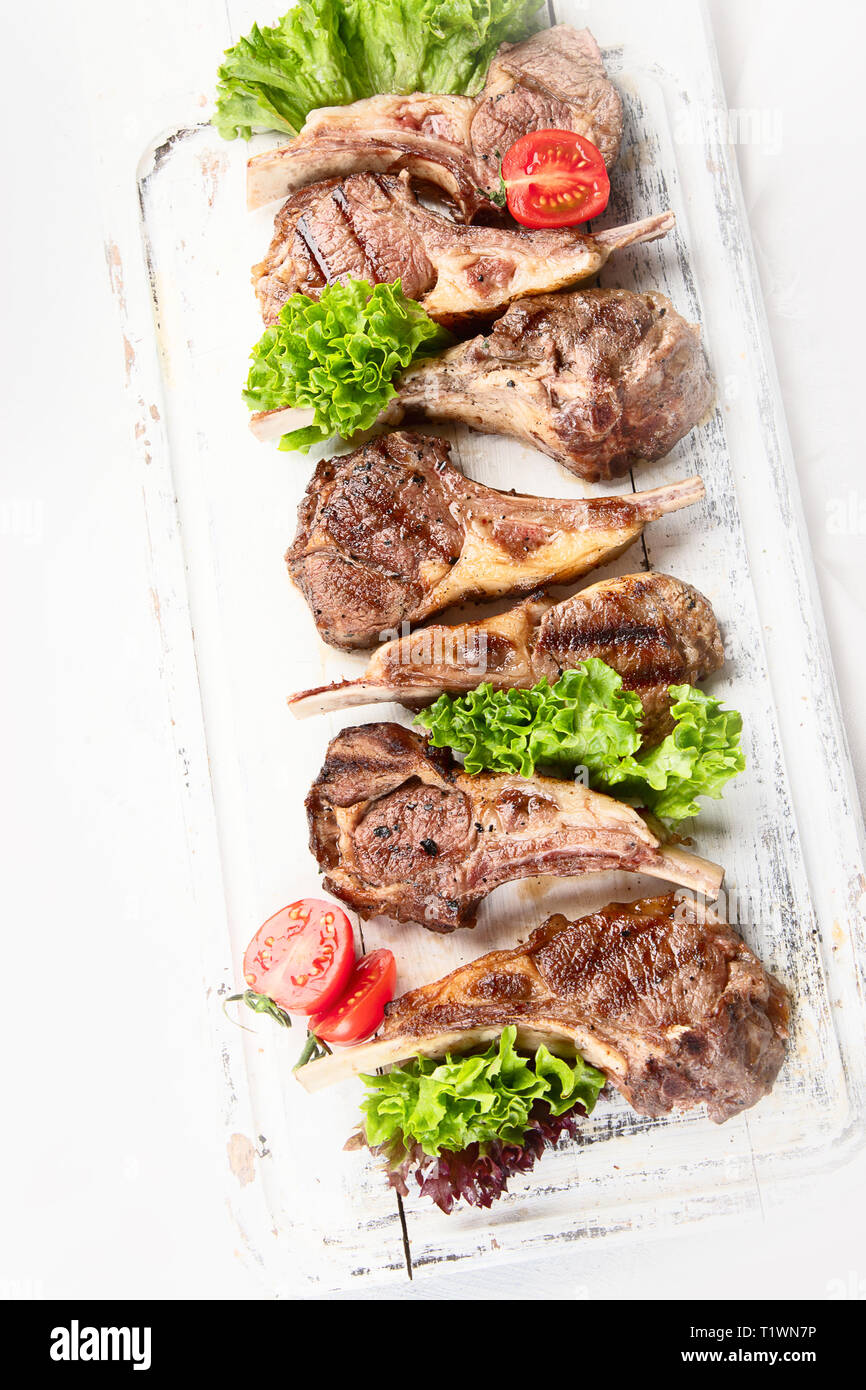 Grilled lamb ribs. Rack of lamb chop on white wooden board. Top view