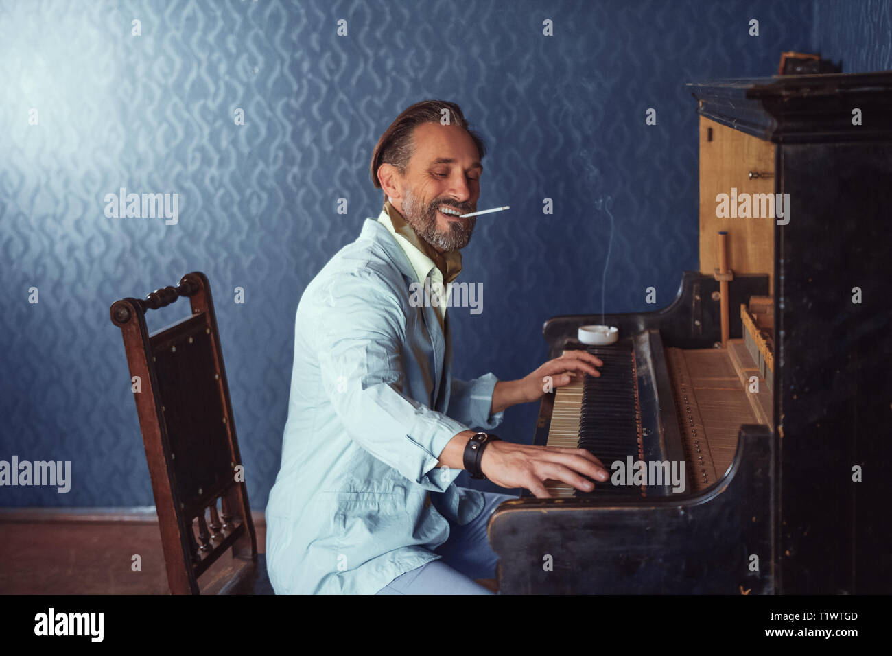 Brutal Man With a Beard 40 Years Old Plays the Old Piano Stock Photo - Alamy