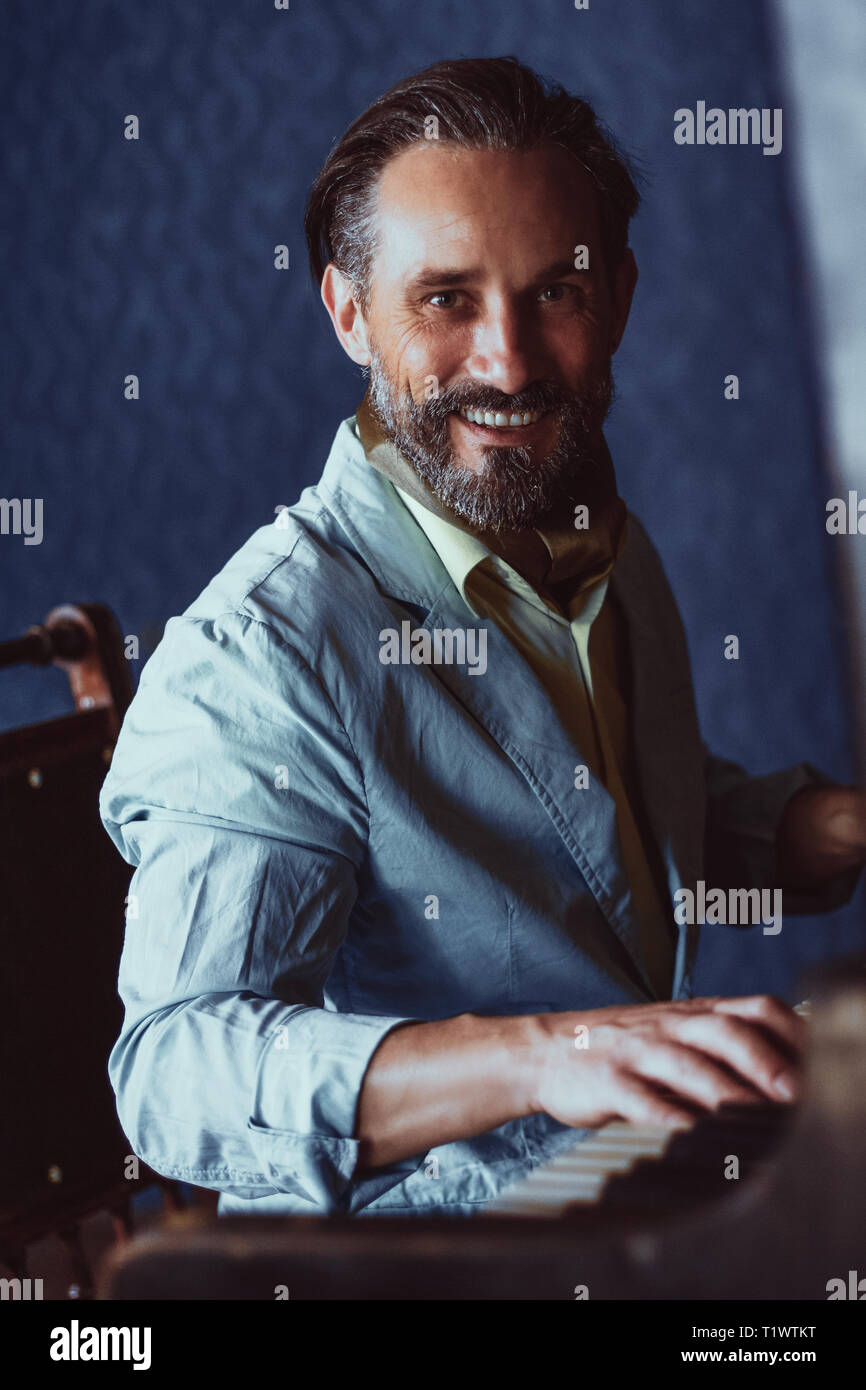 Handsome musician composes music sitting at piano Stock Photo