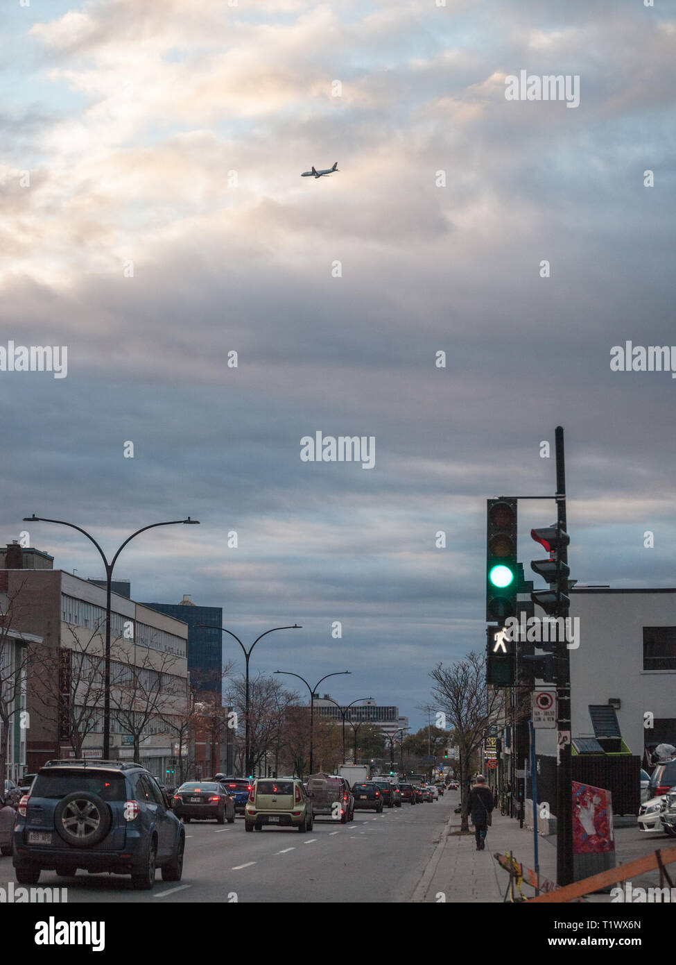 MONTREAL, CANADA - NOVEMBER 8, 2018: Cars driving in a traffic jam on Saint Laurent Boulevard in Montreal, Quebec, in the evening, with a plane landin Stock Photo