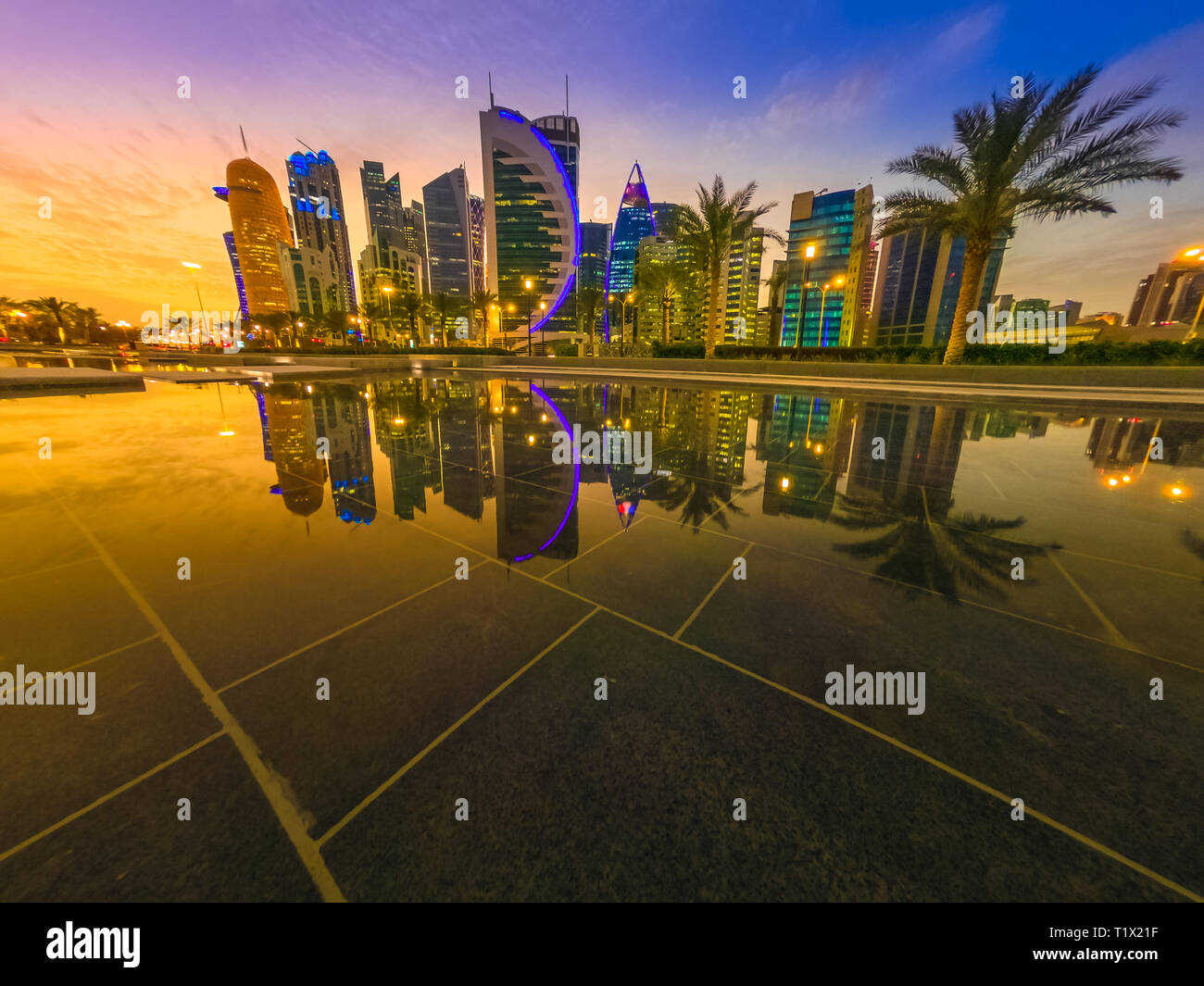 Skyline of Doha, Qatar. Scenic cityscape of West Bay skyline at blue hour reflecting in the water of downtown park. Middle East, Arabian Peninsula in Stock Photo