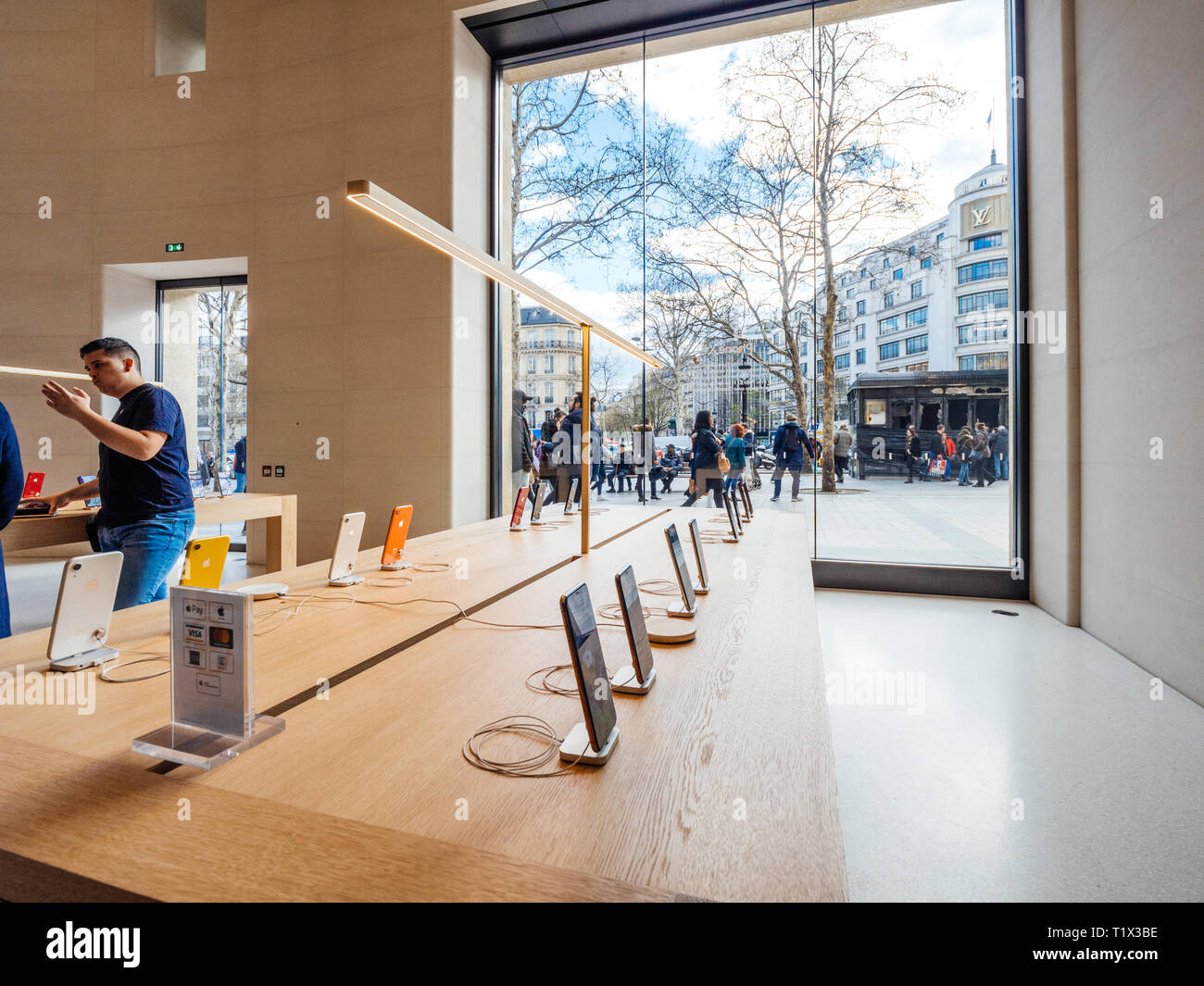 Paris, France - Mar 19 2019: Apple iPhone XS smartphones products are displayed inside the new Apple Store Champs-Elysees with people admiring burnt kiosk outside after yellow vests protest Stock Photo