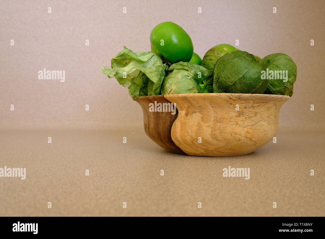 Side view of geen tomatillos (Physalis philadelphica) in a wooden bowl