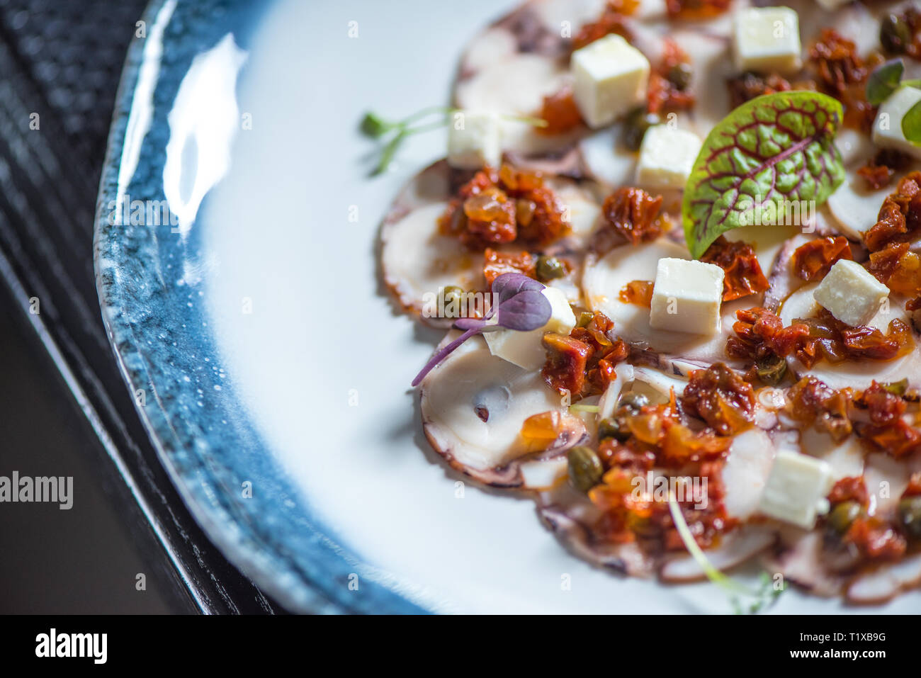 Carpaccio of octopus on blue plate Stock Photo