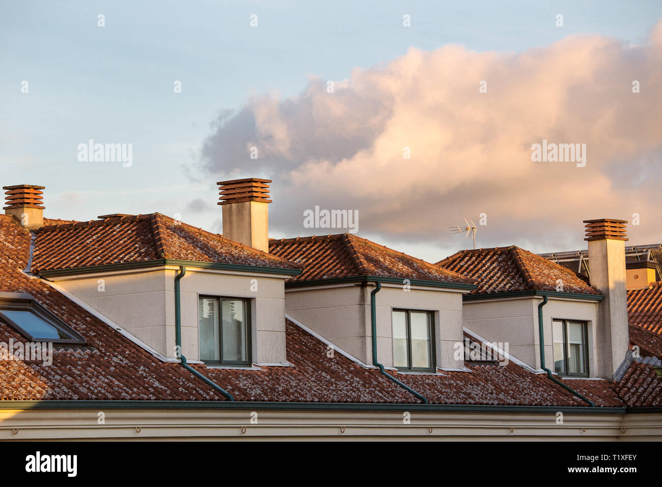 View of of generic Apartment Building With Dormer Windows and clay roof tiles at sunset Stock Photo