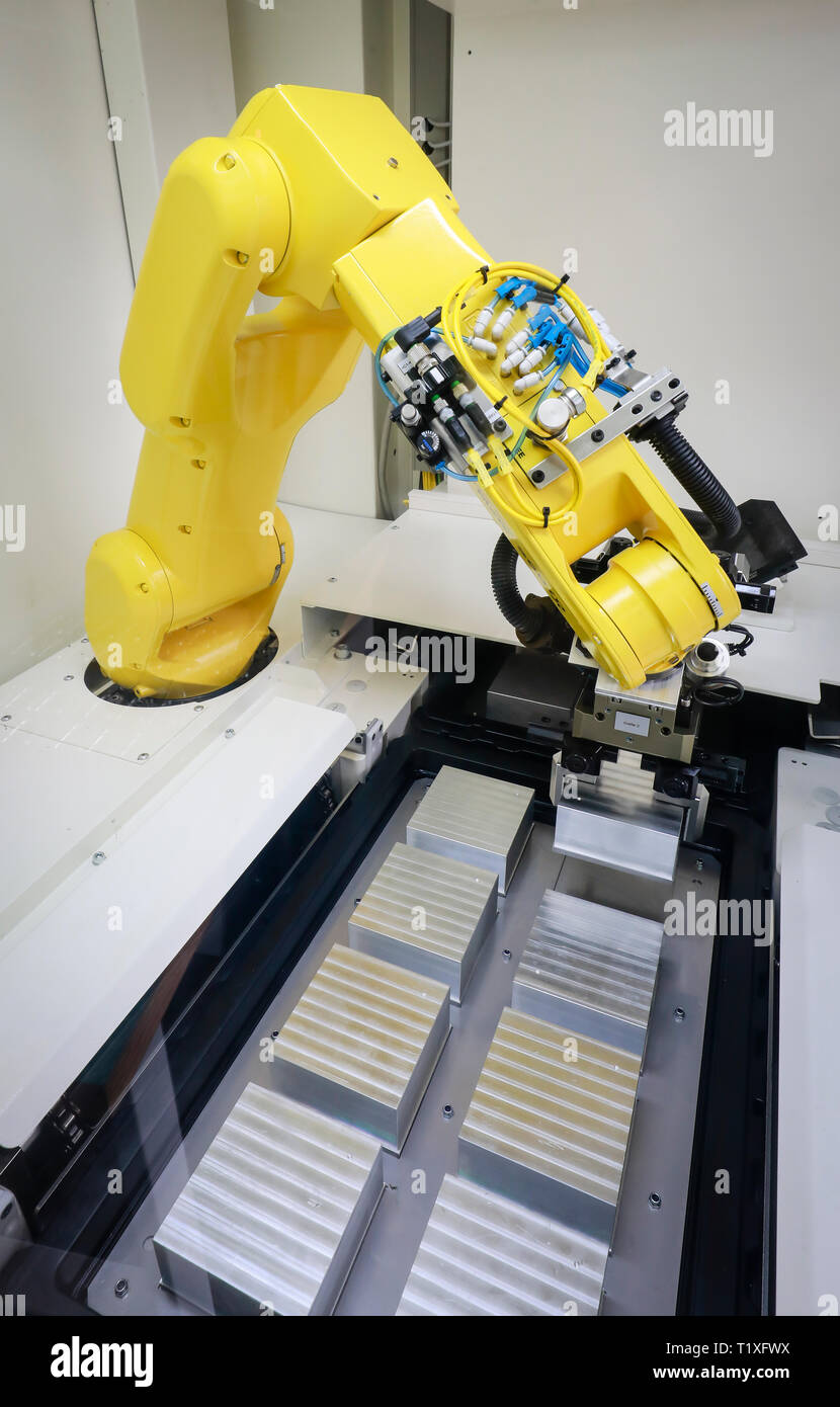 Bochum, North Rhine-Westphalia, Germany - Robot arm equips a CNC milling machine with workpieces here at Stromboli Elektro und Feinwerktechnik on the  Stock Photo