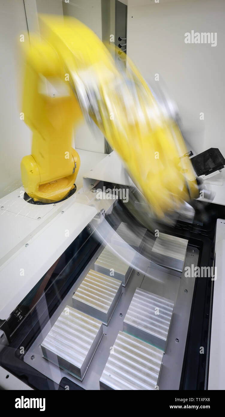 Bochum, North Rhine-Westphalia, Germany - Robot arm equips a CNC milling machine with workpieces here at Stromboli Elektro und Feinwerktechnik on the  Stock Photo