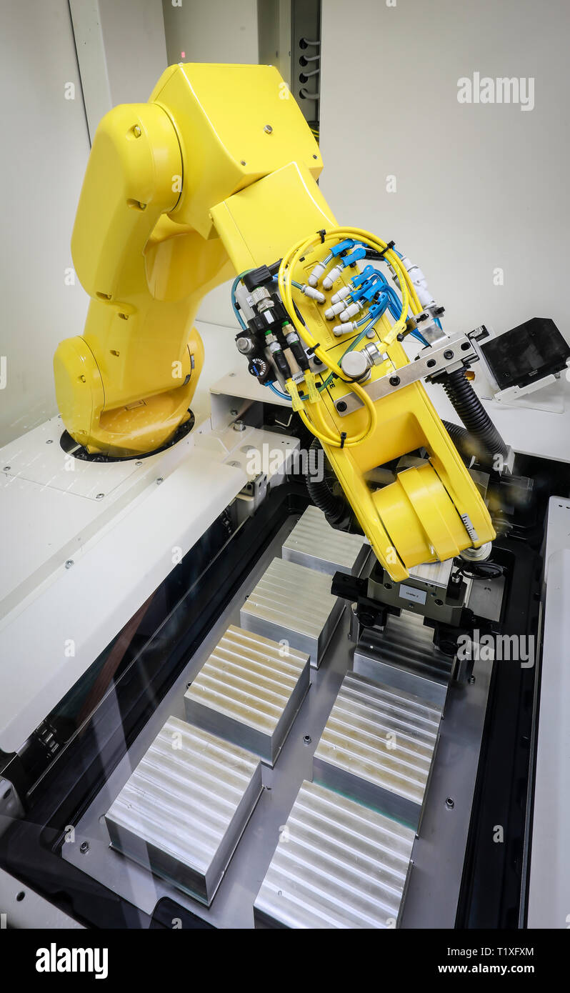 Bochum, North Rhine-Westphalia, Germany - Robot arm equips a CNC milling machine with workpieces here at Stromboli Elektro und Feinwerktechnik on the  Stock Photo
