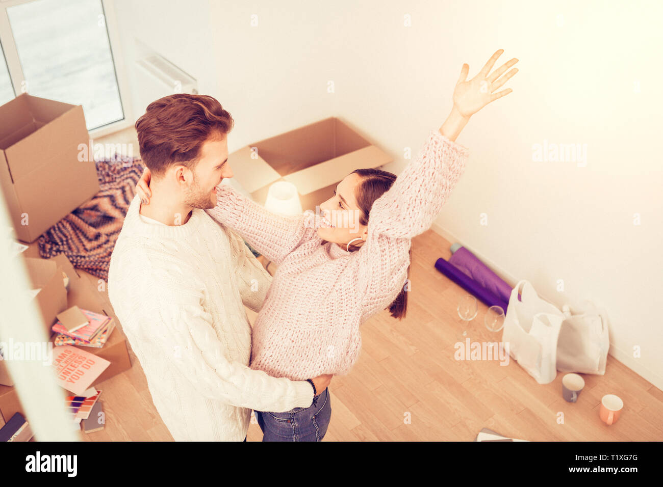 Loving husband hugging his wife standing in room with boxes Stock Photo