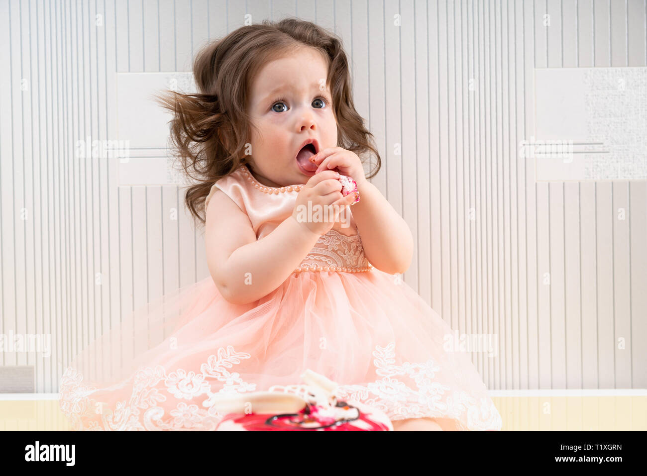Little cute baby girl in pink holiday dress eating sweet cake with her ...