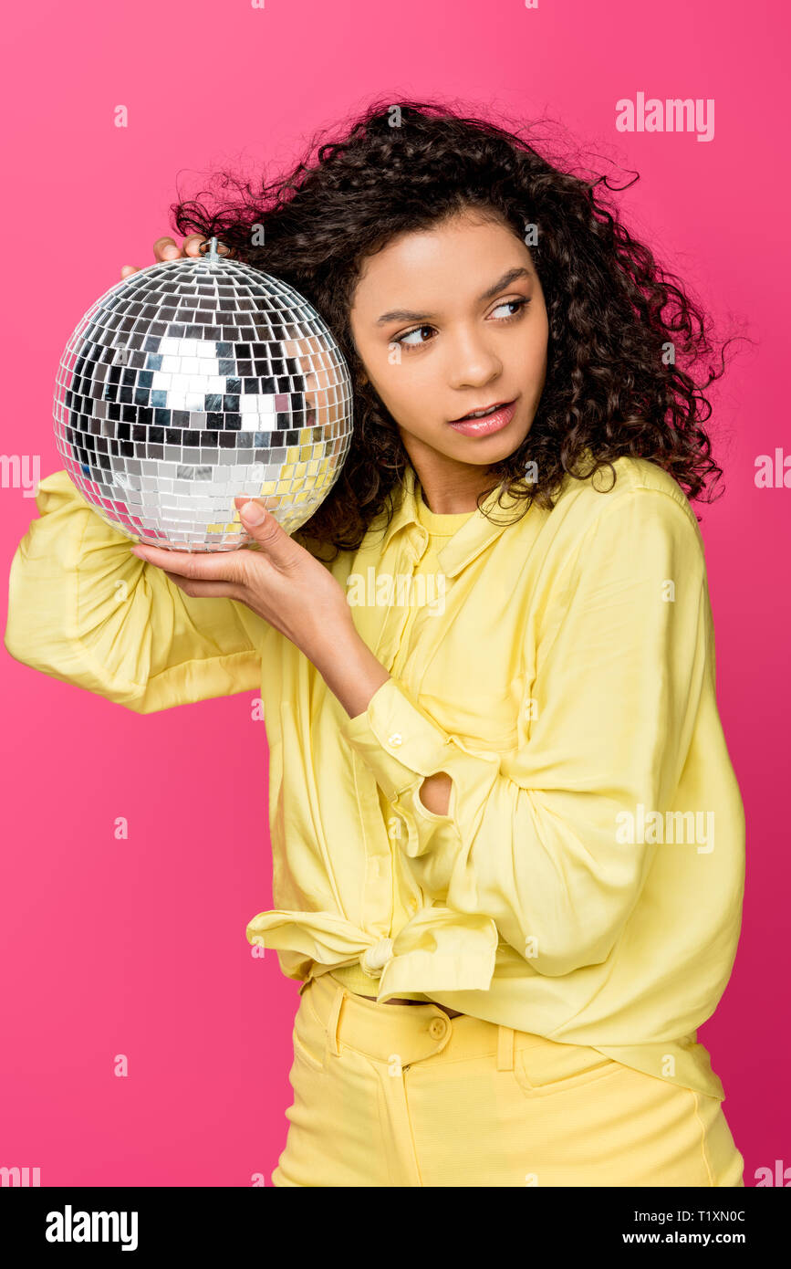 attractive african american woman holding shiny disco ball isolated on crimson Stock Photo