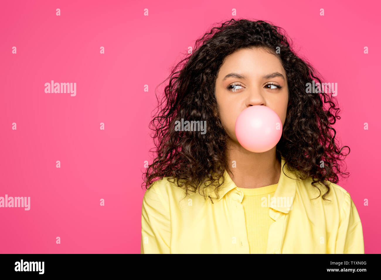 curly african american girl blowing bubble gum isolated on crimson Stock Photo