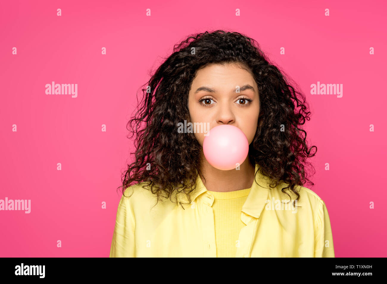 attractive curly african american woman blowing bubble gum isolated on crimson Stock Photo