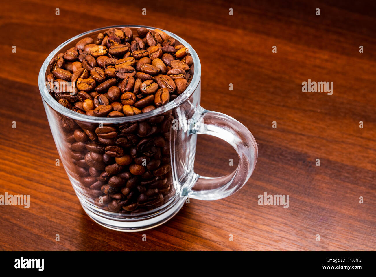 Roasted coffee beans in a glass cup isolated on a rustic dark wood table background Stock Photo