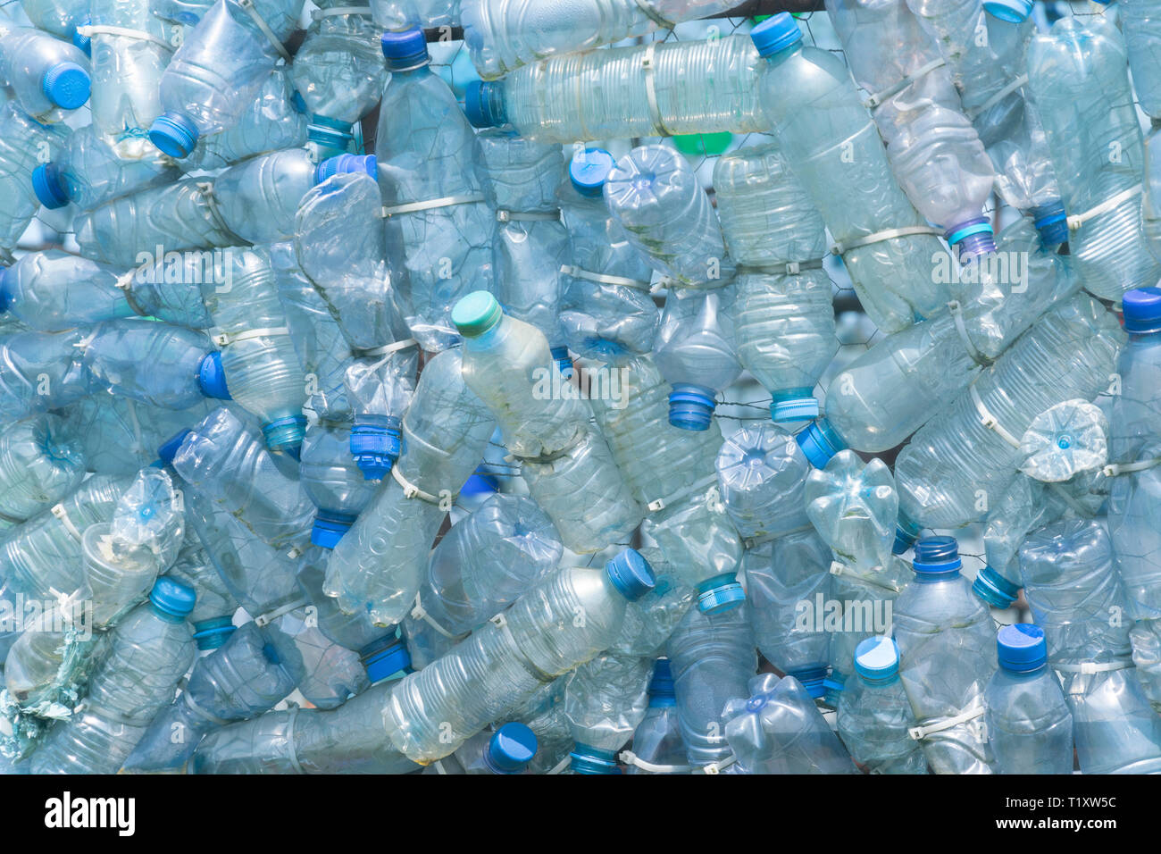 Transparent blank plastic bottles with blue lids, too much plastic waste Stock Photo