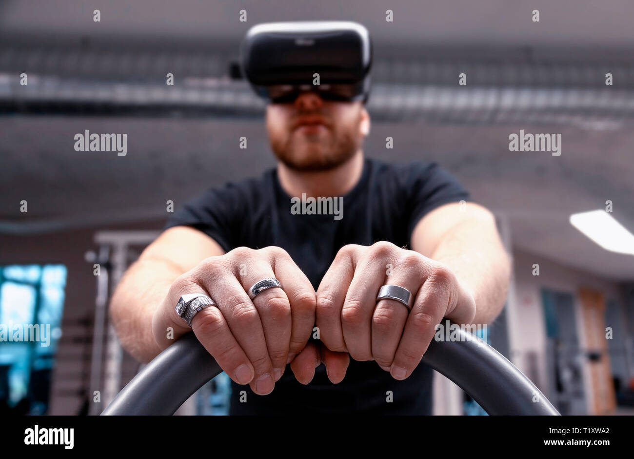 sporty man pedaling on an exercise bike looking through a augmented ...