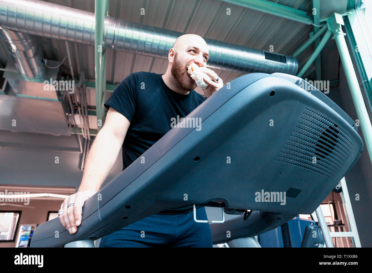 runner athlete while relaxing eating a sandwich on the driving machinery in the gym Stock Photo