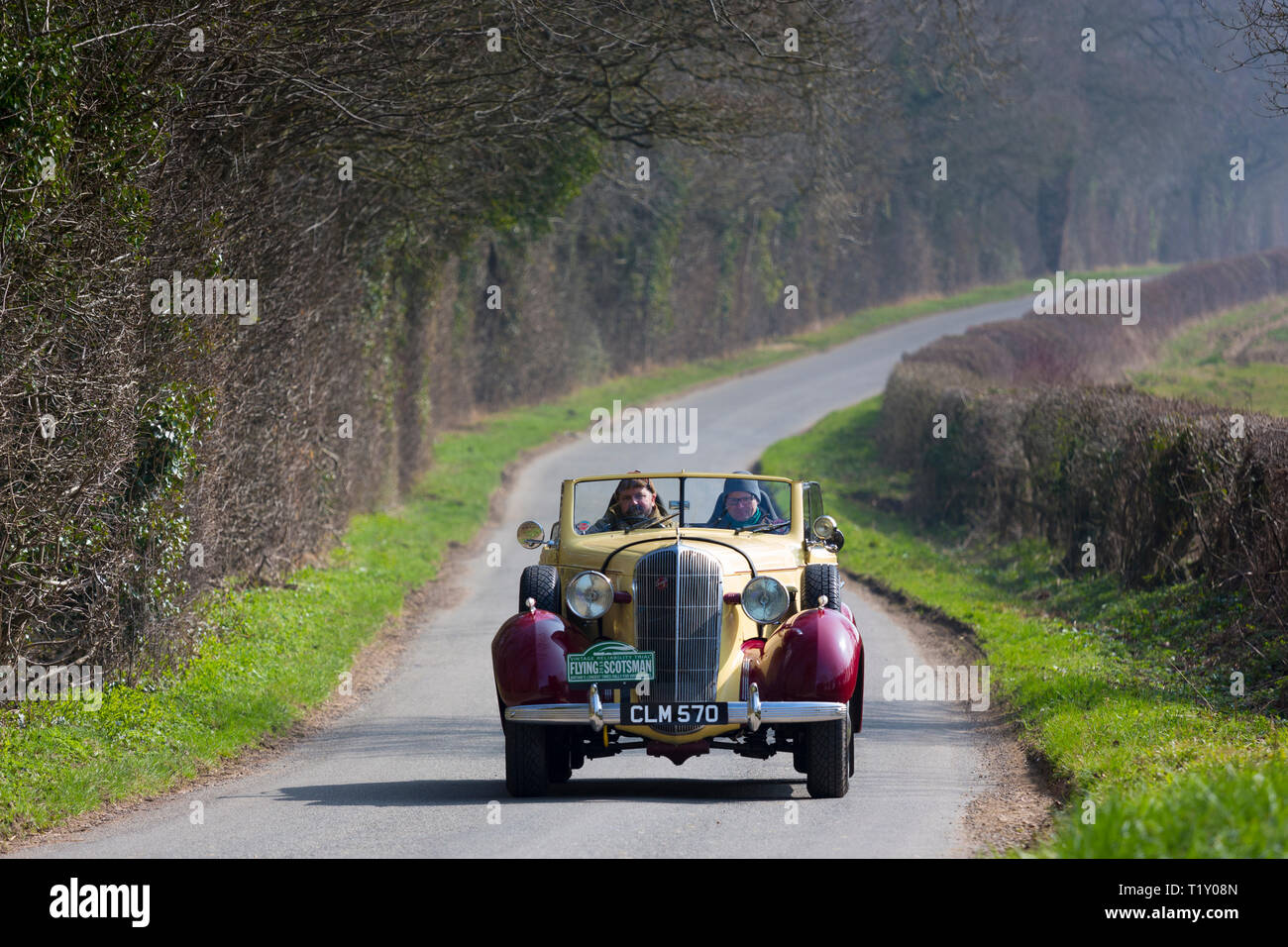Old classic 1936 Buick 40C open top vintageant convertible car driving through country lanes in the Cotswolds, Oxfordshire, UK Stock Photo